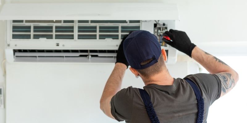 Technician repairing an air conditioning wall unit
